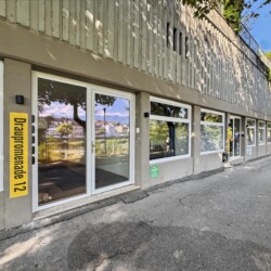 Draupromenade 12 Villach – building entrance with the yellow Draupromenade 12 sign and glass front door