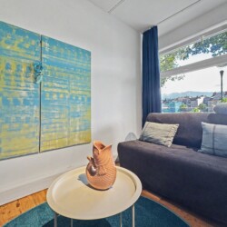 Draupromenade 12 Villach – Top 1 Türkis – two-panel blue-and-yellow painting beside the sofa bed at the window