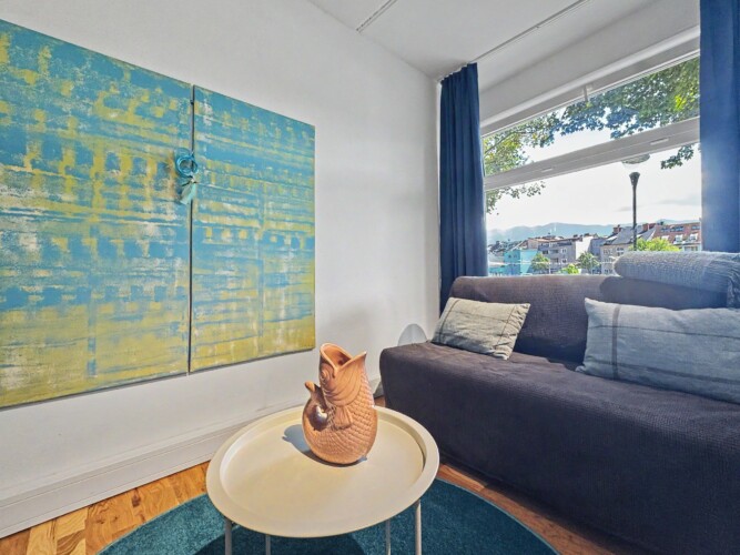 Draupromenade 12 Villach – Top 1 Türkis – two-panel blue-and-yellow painting beside the sofa bed at the window