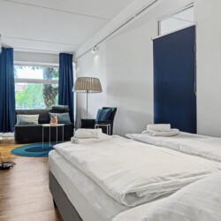 Draupromenade 12 Villach – Top 1 Türkis – king bed with fresh towels, wall-mounted TV and lounge corner behind