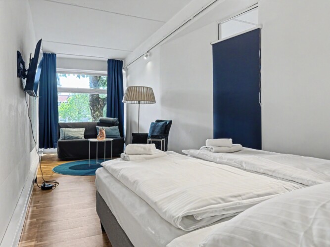 Draupromenade 12 Villach – Top 1 Türkis – king bed with fresh towels, wall-mounted TV and lounge corner behind