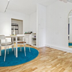 Draupromenade 12 Villach – Top 1 Türkis – round dining table with four chairs and full-length arched brass mirror
