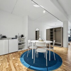 Draupromenade 12 Villach – Top 1 Türkis – kitchenette with sink and two hobs, round dining table and open wardrobe with hanging rail