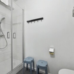Draupromenade 12 Villach – Top 1 Türkis – glass shower cubicle with hand shower on a rail, hook rail and two stools