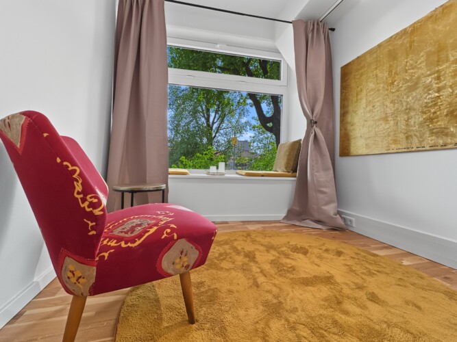 Draupromenade 12 Villach – Top 2 Gold – red vintage armchair beside the padded window seat, gold painting on the wall
