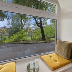 Draupromenade 12 Villach – Top 2 Gold – close-up of the padded window seat with mustard cushions and candles on the wide sill