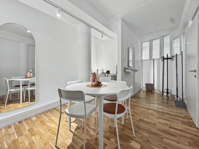 Draupromenade 12 Villach – Top 2 Gold – round dining table with four chairs and full-length arched mirror