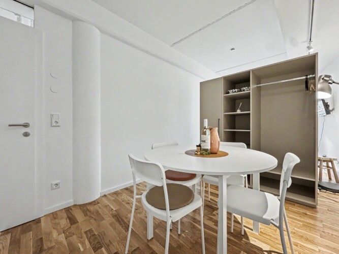 Draupromenade 12 Villach – Top 2 Gold – dining table beside the open wardrobe with hanging rail, hangers and shelves