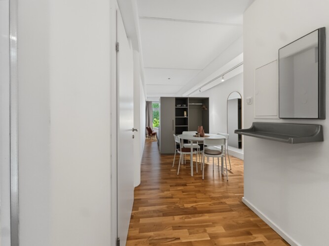 Draupromenade 12 Villach – Top 2 Gold – entrance hallway with mirror and wall console looking through to the dining and sleeping area