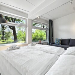 Draupromenade 12 Villach – Top 3 Drau – king bed made up with white linen and folded towels, sofa in the background