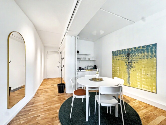 Draupromenade 12 Villach – Top 3 Drau – entrance hallway with gold arched mirror leading to the dining table, kitchenette and round concrete column