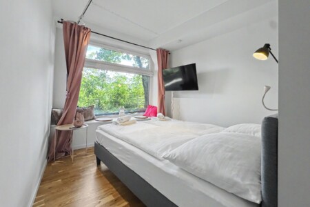 Draupromenade 12 Villach – Top 4 Pink – king bed with dusty-rose curtains, padded window nook and wall-mounted TV