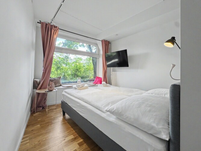 Draupromenade 12 Villach – Top 4 Pink – king bed with dusty-rose curtains, padded window nook and wall-mounted TV