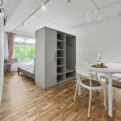 Draupromenade 12 Villach – Top 4 Pink – studio layout with built-in wardrobe separating the king bed from the round dining table