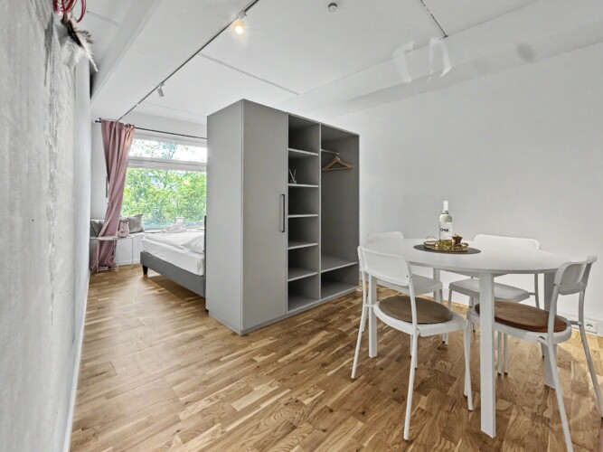 Draupromenade 12 Villach – Top 4 Pink – studio layout with built-in wardrobe separating the king bed from the round dining table