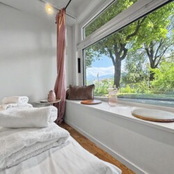 Draupromenade 12 Villach – Top 4 Pink – fresh towels on the king bed beside the cushioned window sill and rose curtain