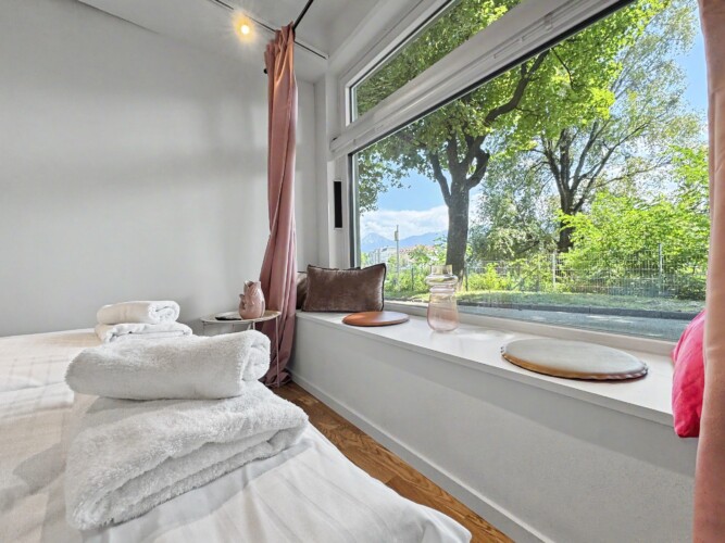 Draupromenade 12 Villach – Top 4 Pink – fresh towels on the king bed beside the cushioned window sill and rose curtain