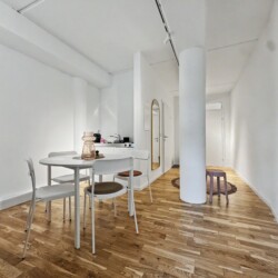 Draupromenade 12 Villach – Top 4 Pink – open living area with round dining table, oak parquet and round concrete column