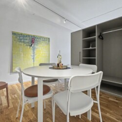 Draupromenade 12 Villach – Top 4 Pink – round dining table with four chairs beside the open built-in wardrobe with hanging rail