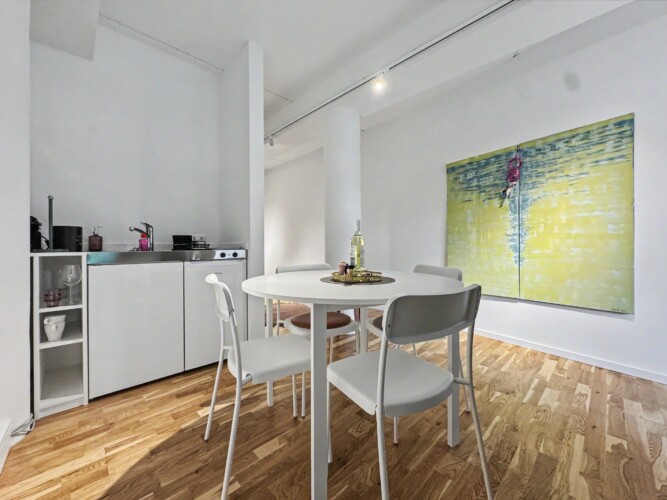 Draupromenade 12 Villach – Top 4 Pink – kitchenette with sink, two hobs, fridge and capsule coffee machine next to the dining table
