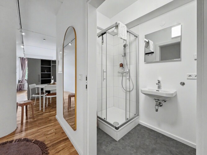 Draupromenade 12 Villach – Top 4 Pink – glass shower cubicle and wall-hung washbasin seen from the hallway