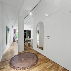 Draupromenade 12 Villach – Top 4 Pink – entrance hallway with round rug and full-length brass arched mirror