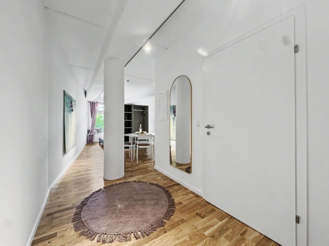 Draupromenade 12 Villach – Top 4 Pink – entrance hallway with round rug and full-length brass arched mirror