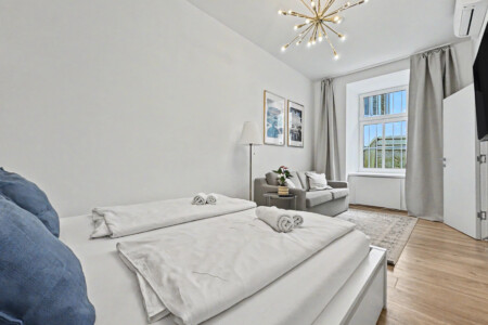 Bright living room with grey sofa, golden accents and high ceilings in Vienna Altbau apartment for 2 guests