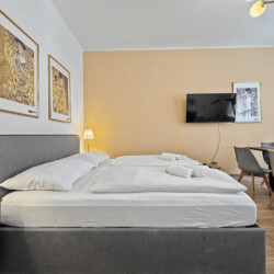 Comfortable double bed with fresh linens and Klimt art print in Vienna short-term rental bedroom
