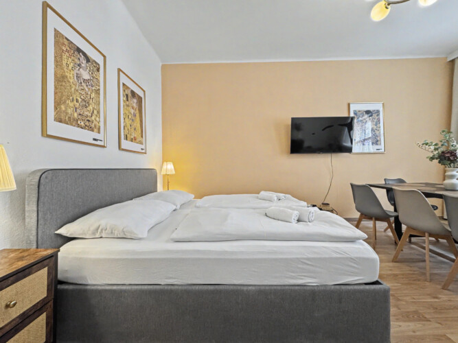 Comfortable double bed with fresh linens and Klimt art print in Vienna short-term rental bedroom